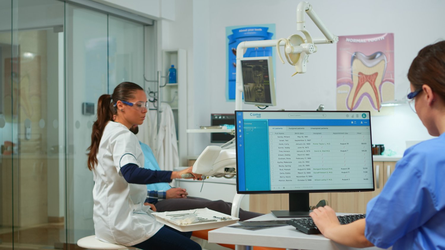 Dental clinic staff managing patient appointments and records on computer while dentist consults with patient, representing professional dental billing services and dental practice management.